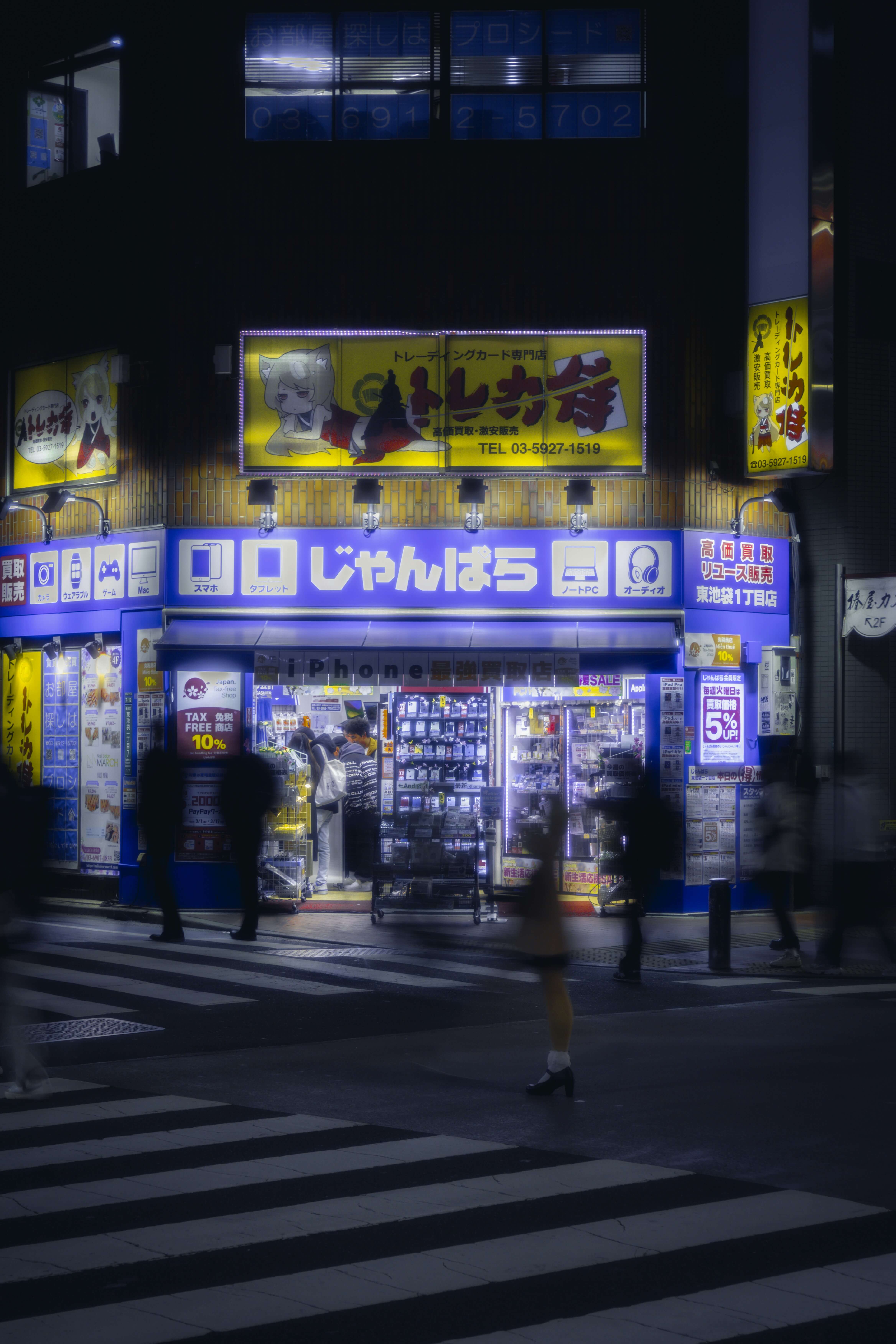 night time Akihabara Japan street scene with corner store and people passing